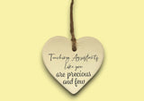 a ceramic heart hanging on a string with a message